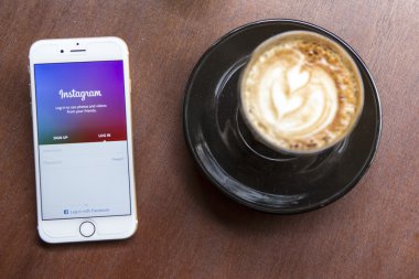 CHIANG MAI, THAILAND - APRIL 22, 2015: Instagram application using Apple iPhone 6 on coffee shop table. Instagram is largest and most popular photograph social networking site in the world.
