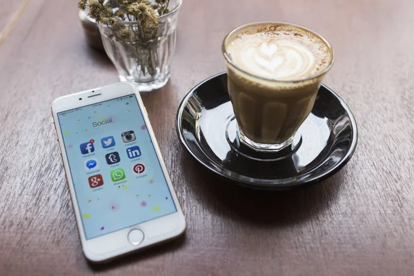 CHIANG MAI, TAILANDIA - 22 DE ABRIL DE 2015: Todos los iconos populares de las redes sociales en la pantalla del dispositivo inteligente Apple iPhone 6 en la mesa de café . — Foto de Stock