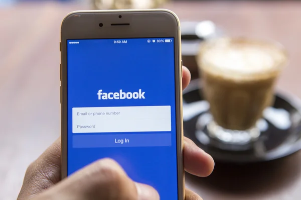 CHIANG MAI, THAILAND - APRIL 22, 2015: A man trying to log in Facebook application using Apple iPhone 6. Facebook is largest and most popular social networking site in the world. — Zdjęcie stockowe