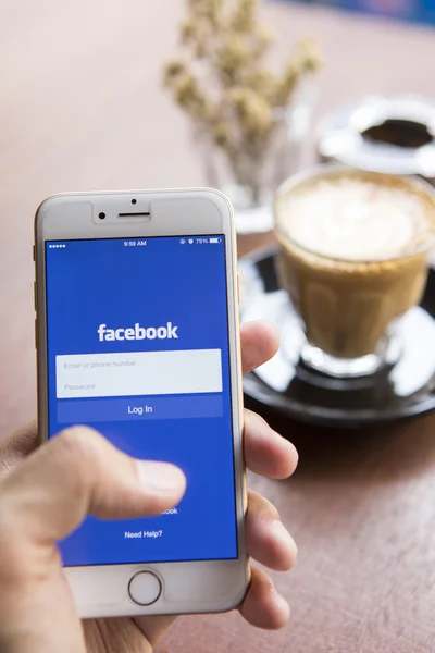 CHIANG MAI, THAILAND - APRIL 22, 2015: A man trying to log in Facebook application using Apple iPhone 6. Facebook is largest and most popular social networking site in the world. — Zdjęcie stockowe