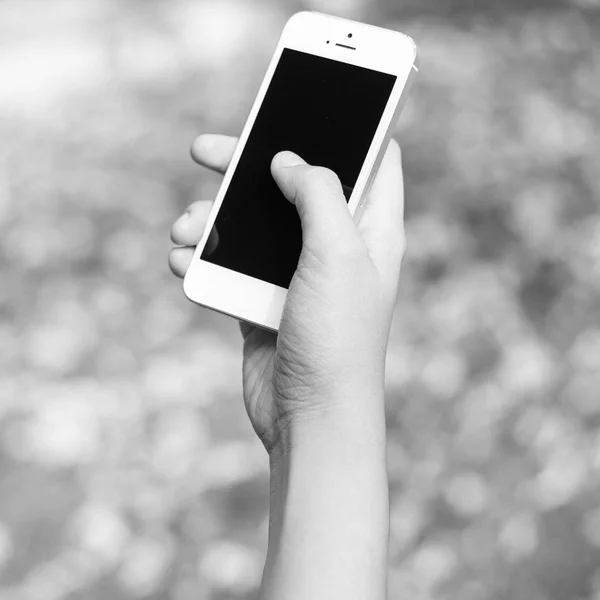 Vrouw hand met smartphone tegen op zwart-witprinter achtergrondkleur — Stockfoto