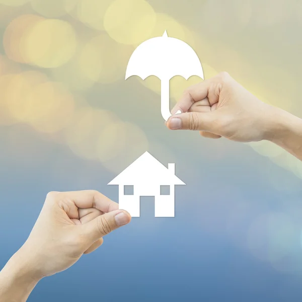 Business concept Hand hold white paper house and umbrella bokeh — Stock Photo, Image