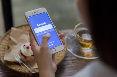 Chiang Mai, Tayland - 28 Haziran 2015: Apple iphone 6 kullanarak Facebook uygulamada oturum çalışan kadın. Dünyanın en büyük ve en popüler sosyal ağ sitesi Facebook olduğunu.