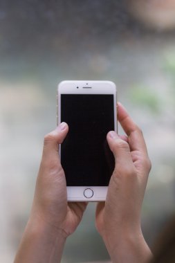 Kadın el smartphone karşı yumuşak kahve dükkanı kafe arka planda üzerinde tutarak.