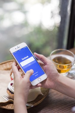 Chiang Mai, Tayland - 28 Haziran 2015: Apple iphone 6 kullanarak Facebook uygulamada oturum çalışan kadın. Dünyanın en büyük ve en popüler sosyal ağ sitesi Facebook olduğunu.