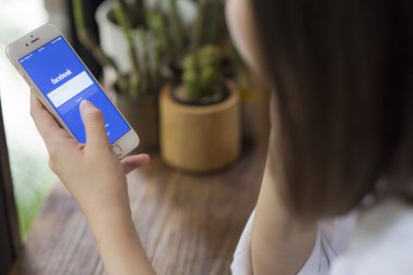 Chiang Mai, Tayland - 28 Haziran 2015: Apple iphone 6 kullanarak Facebook uygulamada oturum çalışan kadın. Dünyanın en büyük ve en popüler sosyal ağ sitesi Facebook olduğunu.