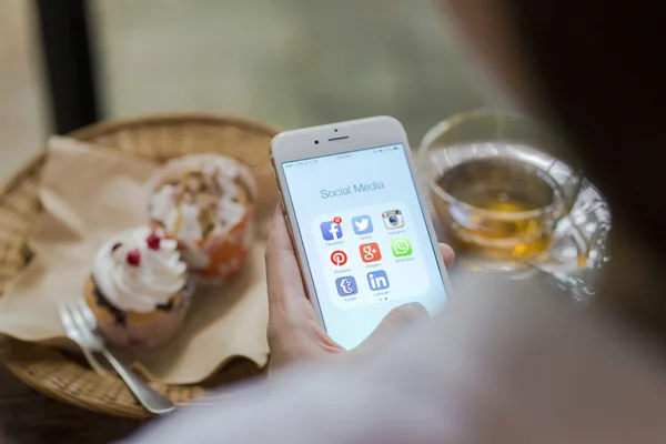 CHIANG MAI, TAILANDIA - 28 de junio de 2015: Todos los iconos populares de las redes sociales en la pantalla del dispositivo inteligente Apple iPhone 6 en la mano de la mujer en la cafetería . — Foto de Stock
