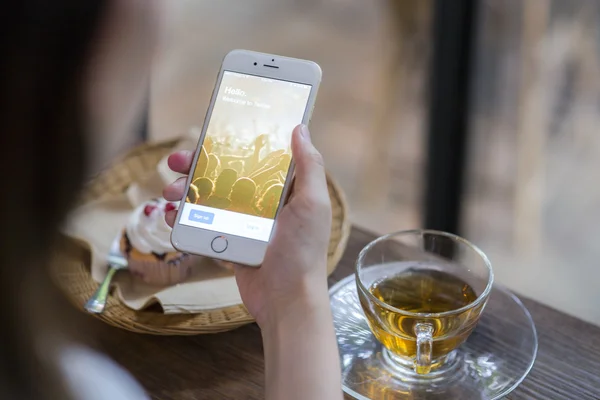 CHIANG MAI, TAILANDIA - 28 DE JUNIO DE 2015: Mujer intentando iniciar sesión en la aplicación de Twitter usando el iPhone 6 de Apple en la cafetería. Twitter es el sitio de redes sociales más grande y popular del mundo . — Foto de Stock