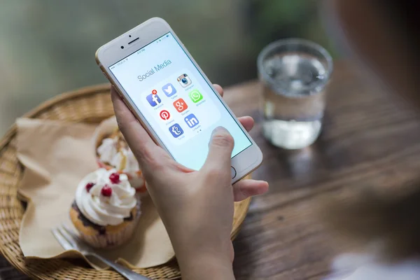 CHIANG MAI, THAILAND - JUNE 28, 2015: All of popular social media icons on smartphone device screen Apple iPhone 6 on woman hand in coffee shop cafe. — Zdjęcie stockowe