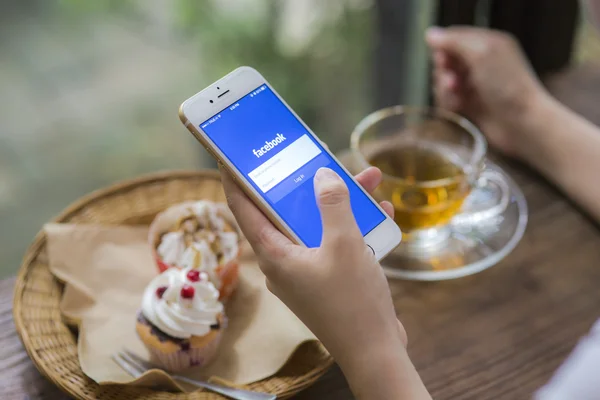 CHIANG MAI, TAILANDIA - 28 DE JUNIO DE 2015: Mujer intentando iniciar sesión en la aplicación de Facebook usando Apple iPhone 6. Facebook es el sitio de redes sociales más grande y popular del mundo . —  Fotos de Stock