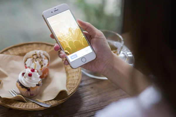 CHIANG MAI, TAILANDIA - 28 DE JUNIO DE 2015: Mujer intentando iniciar sesión en la aplicación de Twitter usando el iPhone 6 de Apple en la cafetería. Twitter es el sitio de redes sociales más grande y popular del mundo . — Foto de Stock