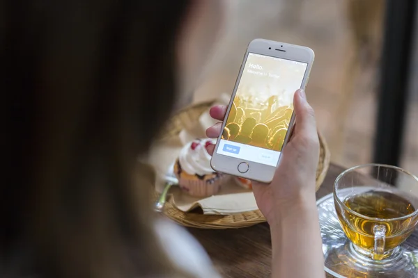 CHIANG MAI, TAILANDIA - 28 DE JUNIO DE 2015: Mujer intentando iniciar sesión en la aplicación de Twitter usando el iPhone 6 de Apple en la cafetería. Twitter es el sitio de redes sociales más grande y popular del mundo . —  Fotos de Stock