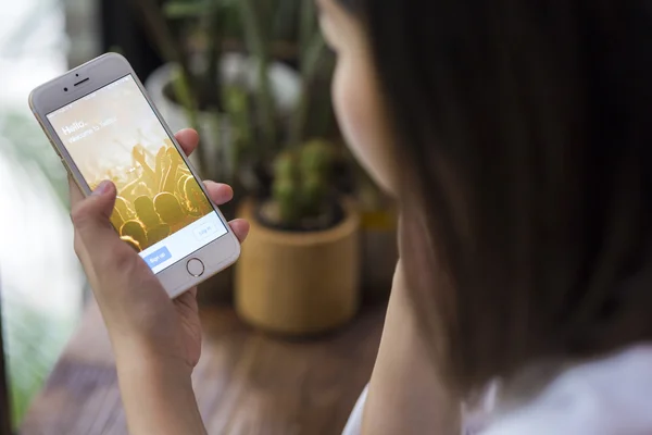 ЧЬЯН-ИЛАНДИЯ, ТАИЛАНД - 28 июня 2015 года: Женщина пытается войти в приложение Twitter с помощью Apple iPhone 6 в кофейне. Twitter является крупнейшей и самой популярной социальной сетью в мире . — стоковое фото