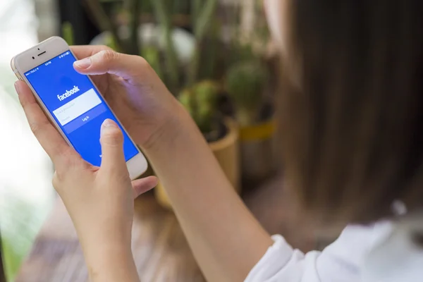 CHIANG MAI, TAILANDIA - 28 DE JUNIO DE 2015: Mujer intentando iniciar sesión en la aplicación de Facebook usando Apple iPhone 6. Facebook es el sitio de redes sociales más grande y popular del mundo . — Foto de Stock