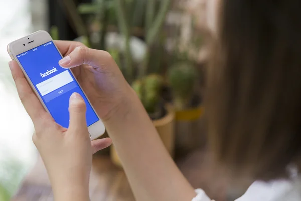 CHIANG MAI, TAILANDIA - 28 DE JUNIO DE 2015: Mujer intentando iniciar sesión en la aplicación de Facebook usando Apple iPhone 6. Facebook es el sitio de redes sociales más grande y popular del mundo . — Foto de Stock