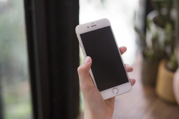 Kadın el smartphone karşı yumuşak kahve dükkanı kafe arka planda üzerinde tutarak. — Stok fotoğraf