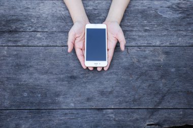 Smartphone ahşap masa üzerinde tutan kadın.