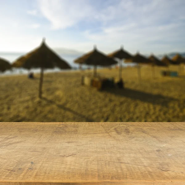 木のテーブルに使用されるぼやけた青い海背景上表示製品 — ストック写真