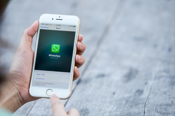 CHIANG RAI, THAÏLANDE - 13 SEPTEMBRE 2015 : Femme essayer d'utiliser le service Internet social WhatsApp écran sur fond bleu. iPhone 6 a été créé et développé par Apple inc . — Photo