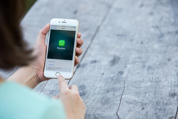 CHIANG RAI, TAILANDIA - 13 DE SEPTIEMBRE DE 2015: La mujer intenta usar la pantalla de WhatsApp del servicio social de Internet sobre fondo azul. iPhone 6 fue creado y desarrollado por Apple inc . — Foto de Stock