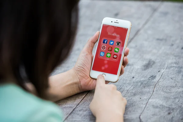 CHIANG RAI, TAILANDIA - 13 de septiembre de 2015: Mujer sosteniendo el iPhone de Apple muestran todos los iconos populares de las redes sociales en el fondo de la pantalla del dispositivo inteligente . — Foto de Stock