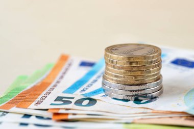 Bej bir masanın üstündeki bir kaç avroluk banknota yığınla para. Zenginlik, nakit tasarrufu, gelir ve gider hesapları. Yüzeyin derinliği. Ön görünüm.