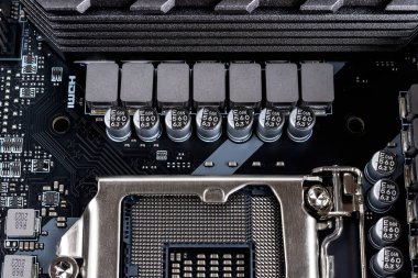 Modern siyah bir anakart üzerinde işlemci soketi çalıştırmak için indüktörler ve kapasitörler. Bilgisayar ana devre bileşenleri. Masaüstü donanım makrosu. Montaj, güncelleme ve onarım için bilgisayar parçaları. Ön görünüm.