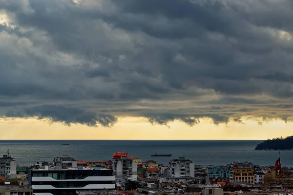 Dramatic landscape of stormy sky over small seaside city. The sky turned yellow before the storm. Dark nimbostratus clouds hang over town and sea. Weather forecast and meteorology. Outdoors.