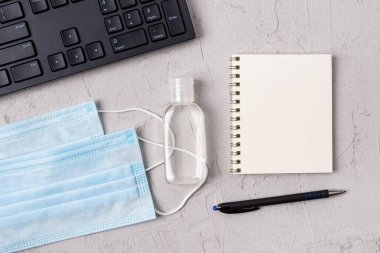 Tıbbi yüz maskesi, el dezenfektanı ve PC klavyesinin yanındaki yay defterine boşluk kopyala. Covid, grip ve viral enfeksiyonlara karşı koruma, konsept. Üst görünüm.