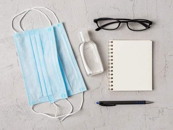 Blue Medical Face Mask Hand Sanitizer Glasses Pen Paper Notebook — Stock Photo, Image