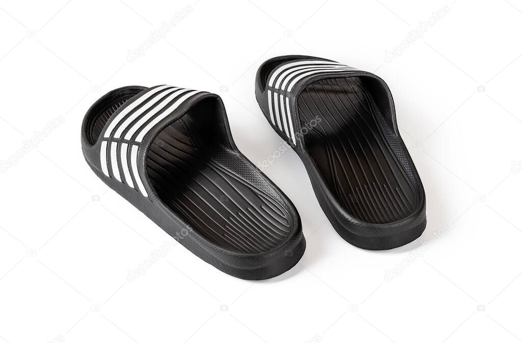 Pair of rubber slippers isolated on white background. Black slide sandals close-up. Light flip flops for pool or shower. Comfortable beach shoes for hot weather and summer vacation. Back view.