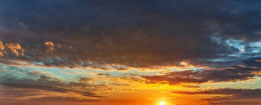 Batan güneş, yaklaşan koyu renk yağmuru altın turuncu bir rengi bulutlandırıyor. Fırtınadan önce etkileyici bir gün batımı. Altın saat dramatik gökyüzü. Gökyüzündeki günbatımı ateşinin geniş bir görüntüsü. Doğada güzellik.