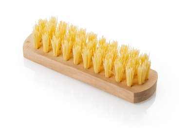 Beyaz arka planda izole edilmiş sert sarı kılları olan yeni ahşap temizlik fırçasına yakın plan. Ev işleri ve temizlik malzemeleri için klasik tasarım öğesi. DoF dolu. Yan görünüm.
