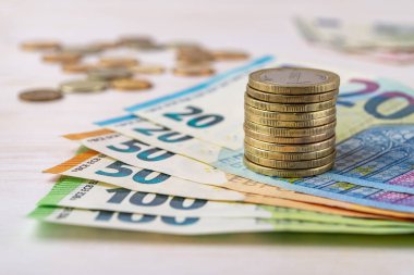 Avro banknotlarına yığınla bozuk para. Masanın üzerinde fan şeklinde banknotlar. Maaş ve maaş kavramları, gelir ve giderlerin hesabı, para sayma, nakit tasarrufu ve zenginlik. Ön görünüm. 