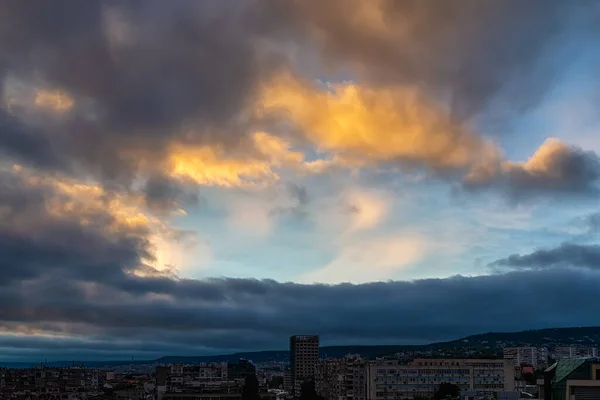 Dark rain clouds are approaching the city and covering the clear blue sky at evening. Clear sky is visible through the gap in the dark gloomy clouds. Dramatic landscape. Weather forecast, meteorology. Outdoors.