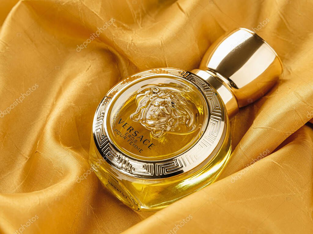 Varna, Bulgaria, August 14, 2021. Glass bottle of Versace Eros Pour Femme perfume against gold colored silk satin folds. Produced by Gianni Versace italian luxury fashion company. Top view.