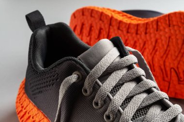 Gri ağ kumaşlı lastik ayakkabı bağcıkları ve turuncu ayakkabılar. Modern tekstil eğitmenlerini spor, spor, spor ve aktif yaşam tarzı için bağlıyor. Bir çift yeni spor ayakkabısı..