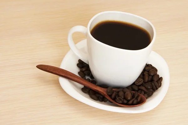 Una taza de café sobre una mesa con una cuchara de madera — Foto de Stock
