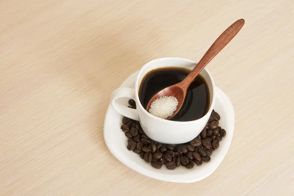 Filiżankę kawy na stole z drewnianą łyżką i cukru — Zdjęcie stockowe