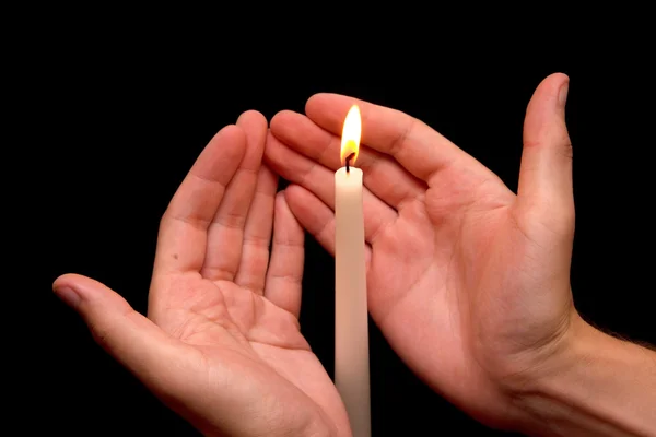 Manos sosteniendo una vela encendida en la oscuridad Imagen De Stock