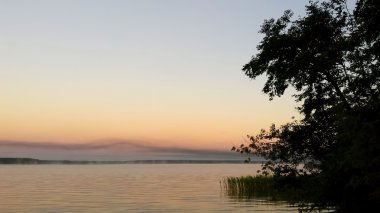 Sis ile bulutsuz bir havada göl günbatımı