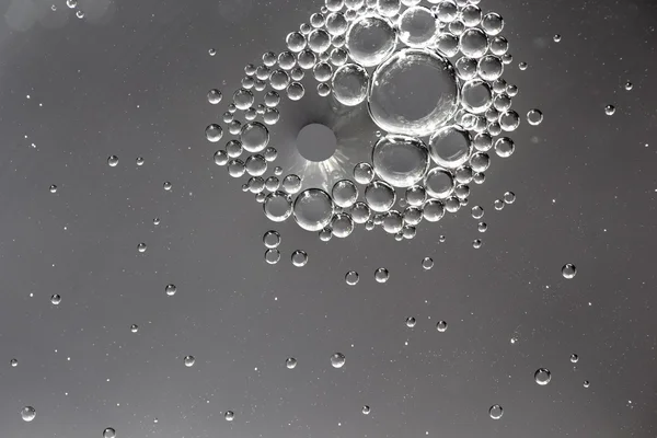 Oil drops in water on a gray background — Stock Photo, Image