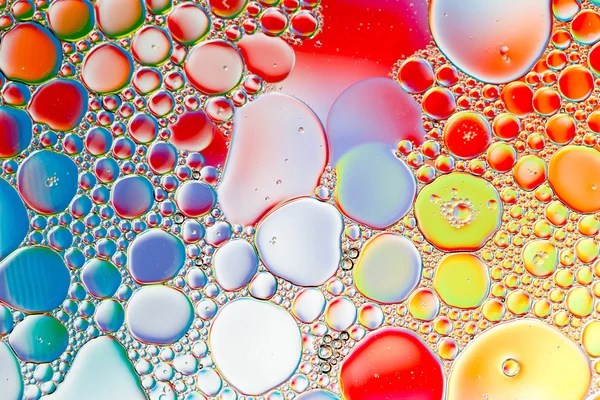 Oil drops in water on a coloured background — Stock Photo, Image