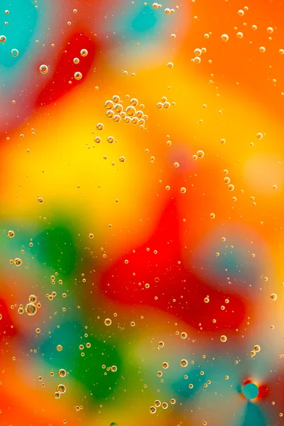 Gotas de aceite en el agua sobre un fondo coloreado — Foto de Stock