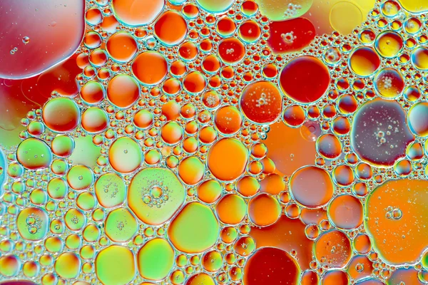Kapky oleje ve vodě na barevném pozadí — Stock fotografie