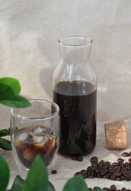 Kahve çekirdekleri ve yeşil yapraklı taze buzlu kahve.