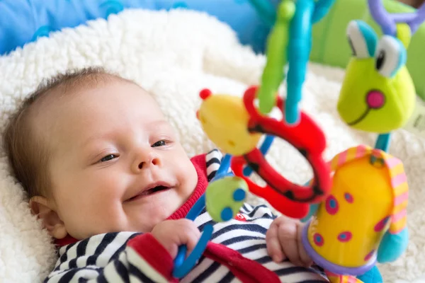 ぶら下がっているおもちゃで遊んで幸せな赤ちゃん — ストック写真