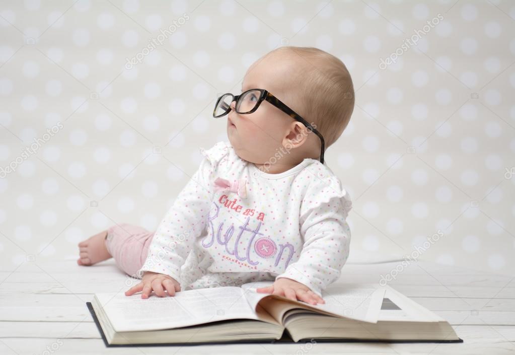 Funny baby girl reading a book