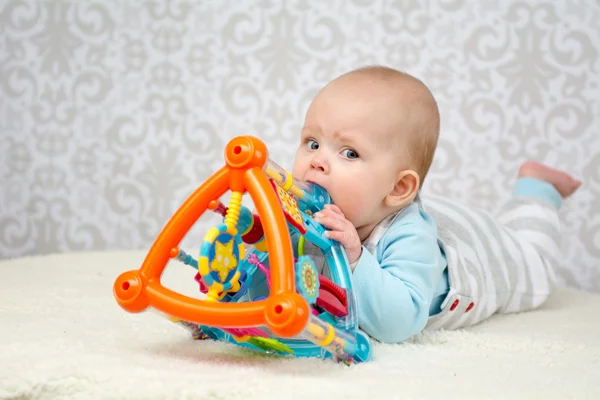 Modré oči dítěte kousat hračku — Stock fotografie