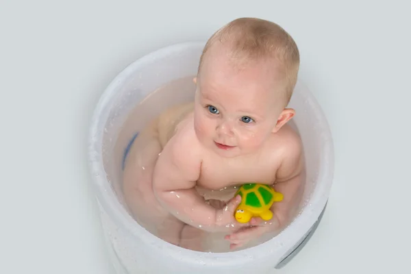 Roztomilé miminko se koupe v průhledný kbelík a hraní s hračkami — Stock fotografie